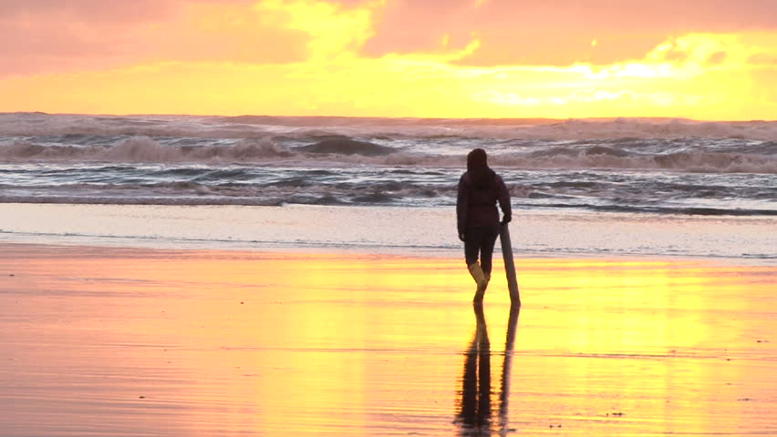 Person with clamming gun walks Pacific Ocean coastline in search for razor clams