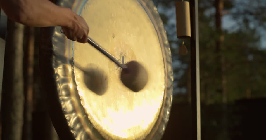 Cinematic Footage with Warm Glow of Sunset. Person Making a Gong Bath Ritual in Open Air. Sound Helping Anonymous Yogi Focus to Transition Deeper Into Meditation and Heal