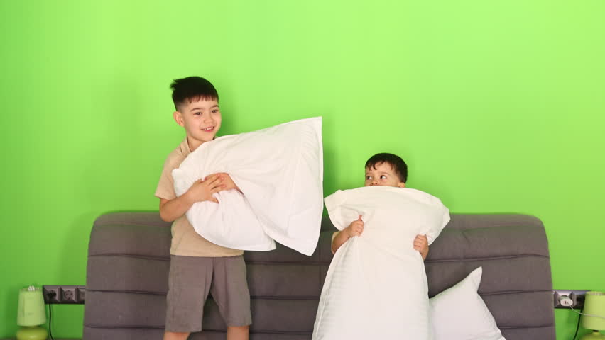 kids are playing in bedroom,jumping on bed,fighting with pillows. siblings are having fun in morning,lying down and smiling,enjoy time together.happy childhood.vertical video