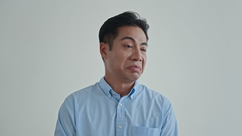 Medium close up of arrogant Asian man looking down upon isolated on white background, copy space