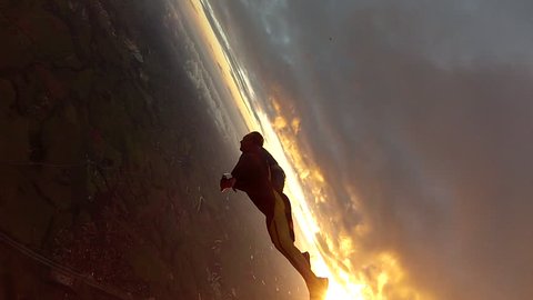 Skydiving wing suit entering the clouds at sunset, adventure freedom concept.