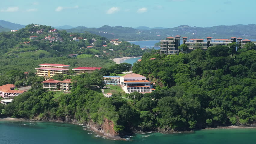 Experience the breathtaking aerial perspective of Santa Cruz in Costa Rica, where the lush greenery meets stunning coastal views and vibrant buildings, all captured in amazing 4K resolution