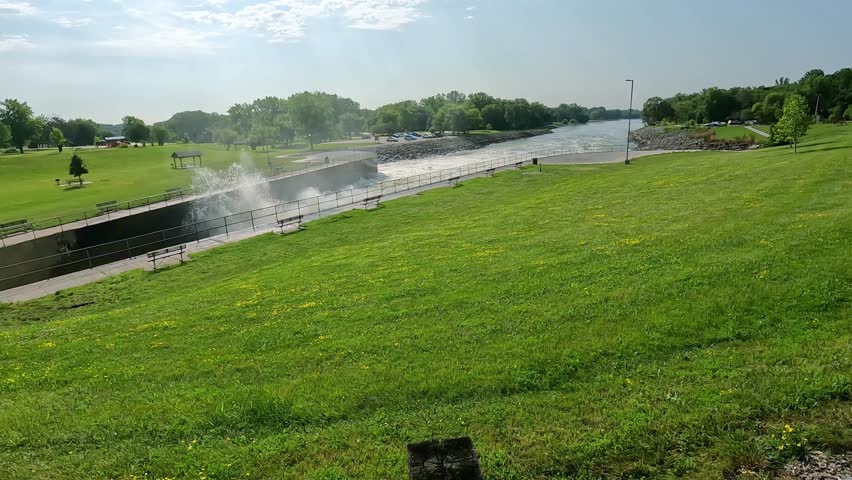 Slow pan of the turbulence from the outflow of Saylorville Lake and Des Moines River with sidewalks and benches in Central Iowa; concepts of flood control, power generation and recreational parks