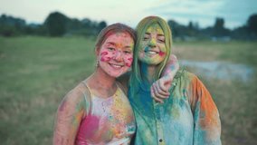 Two girls covered with colorful holi powder are laughing and enjoying the event on a field - Powered by Shutterstock - Get 15% off with code: PIKWIZARD15