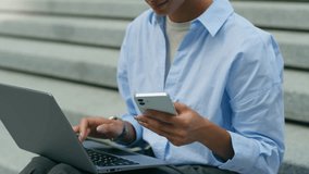 Multitasking African American woman ethnic business lady typing laptop in city outside office using mobile phone girl female businesswoman entrepreneur urban sit working computer holding smartphone - Powered by Shutterstock - Get 15% off with code: PIKWIZARD15
