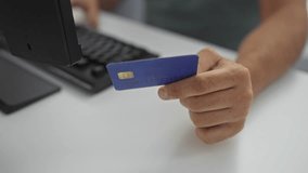 Man holding a blue credit card while typing on a keyboard in an office setting, depicting an indoor workplace environment with hands engaged in an online transaction - Powered by Shutterstock - Get 15% off with code: PIKWIZARD15