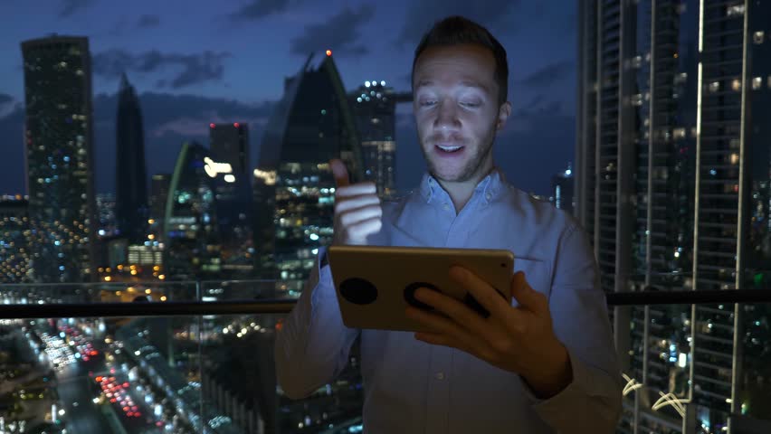 Male Entrepreneur Immerses Himself in Touch Device with City Lights on Window