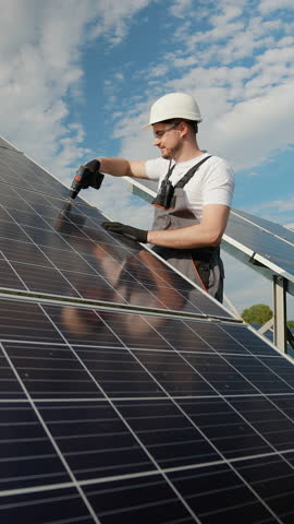 Engineer repairing solar panels with a drill under the sun