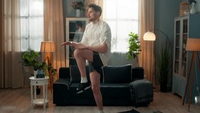 Happy tired smiling sporty Caucasian healthy man male trainer guy sportsman exercising active jumping run on spot touching knees jog training leg cardio workout fitness wiping sweat indoors home room - Powered by Shutterstock - Get 15% off with code: PIKWIZARD15