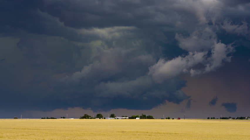 Menacing storm clouds swirl rapidly over a small farm, creating a tense and dramatic atmosphere as the storm intensifies.