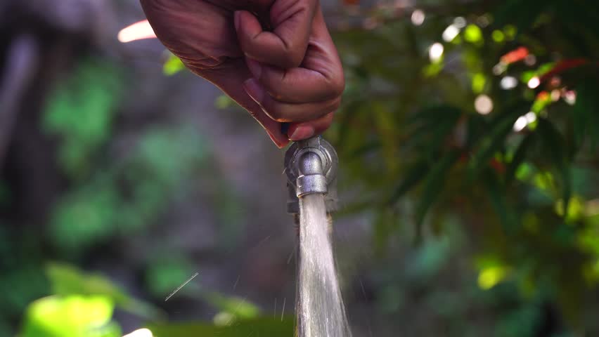 Hand opens the water tap, water flows rapidly. Focus selected. Blurred background