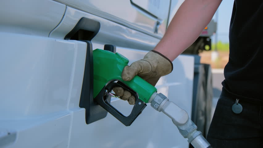 The driver refuels the semi truck. Petrol station with gas pumps. Close up shot view