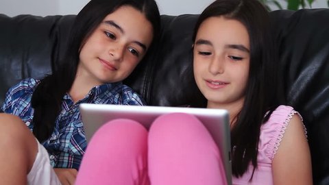 Two happy teenage girls having fun using tablet computer