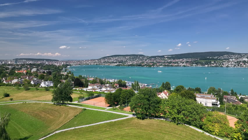 Lake zurich on a sunny day with surrounding landscape and buildings in view, aerial view