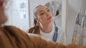 Woman inspecting room renovation coordinate husband work closeup. Focused wife help to hang artwork on wall new apartment. Happy newlyweds decorating modern home with paintings together after moving. - Powered by Shutterstock - Get 15% off with code: PIKWIZARD15