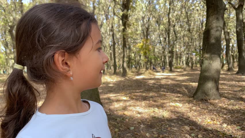 A kid without two front teeth smiles in an autumn park