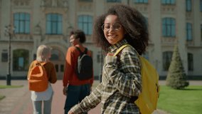 Three multiracial student friends African American guy male man Caucasian women females girls walking going outdoors outside of college academy university high school back view turn around smiling - Powered by Shutterstock - Get 15% off with code: PIKWIZARD15