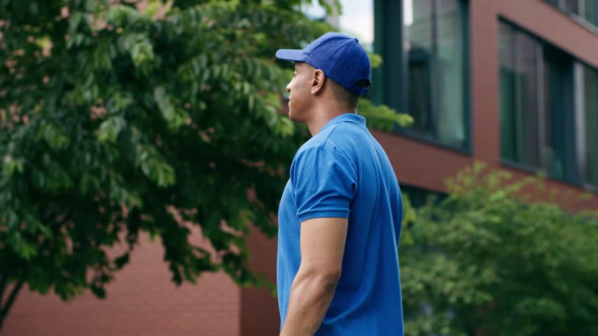 African American delivery food post service man courier in uniform in city worker deliver guy male hold delivered order meal shopping purchase package smiling happy postman holding showing paper bag
