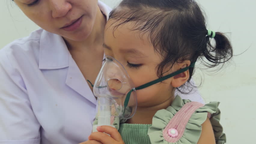 doctor applying medicine inhalation treatment on a toddler baby girl. child with a nebulizer mask at hospital