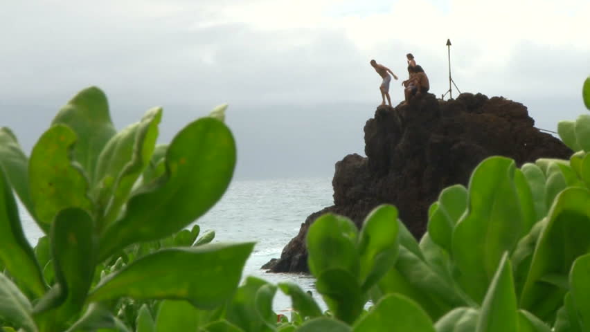 People on cliff in Maui, Hawaii jump off into the Pacific Ocean.