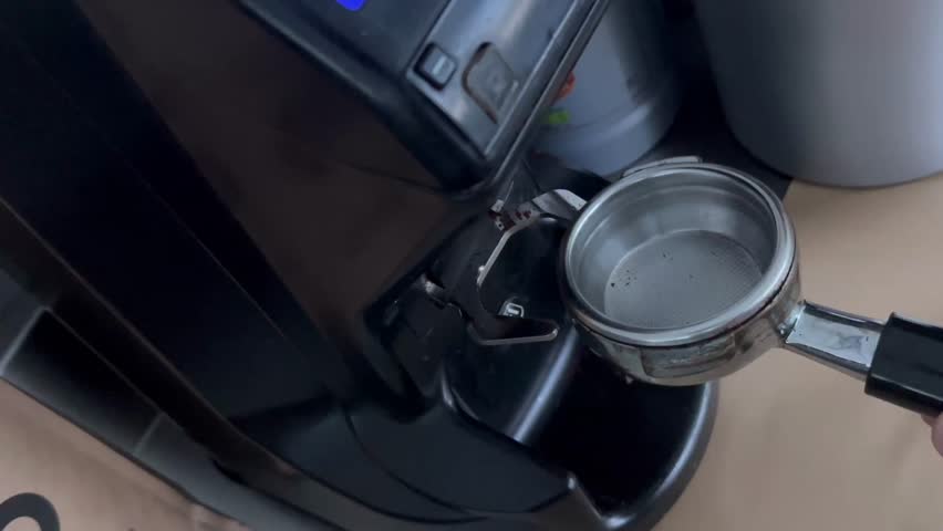 Barista using a tamper to press ground coffee into a portafilter