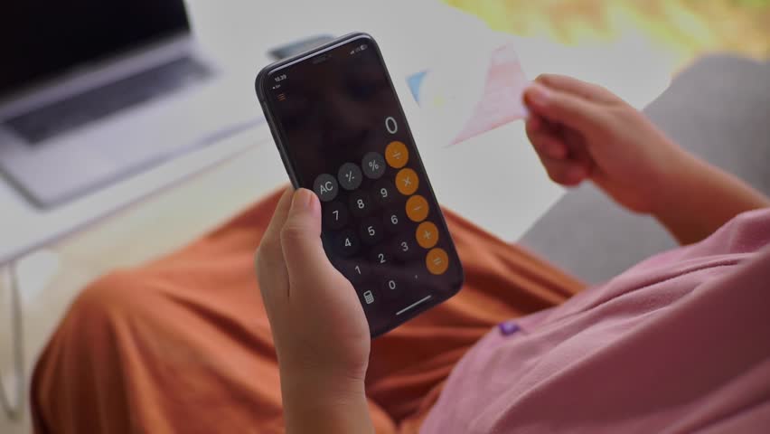 Rear view of a woman wearing a hijab holding a smartphone for open calculator and ATM card, illustration for online transactions or internet banking