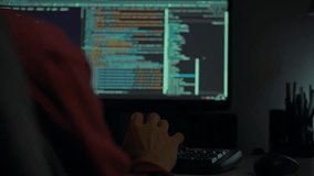 A person sits at a desk focused on coding in a dark room. The computer screens display lines of code, casting an ambient glow over the workspace, ideal for late-night programming sessions - Powered by Shutterstock - Get 15% off with code: PIKWIZARD15