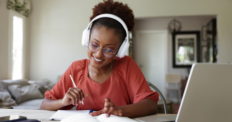 Student woman wear wireless headphones holds pencil writes task, doing university assignment using laptop, participate in on-line class, listen audio course, improve foreign language skills using tech