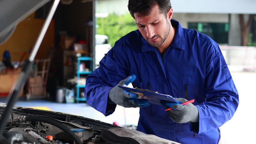 hispanic latin male mechanic repairs car in garage. Closeup hand. Auto car mechanic checking the oil level of the car engine. Car repair and maintenance