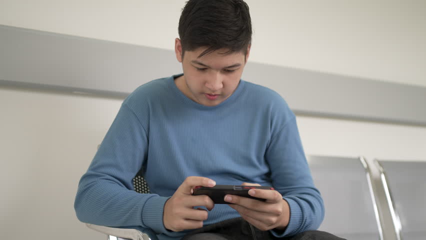 Male teenager patient play mobile phone. Teenager, technology.