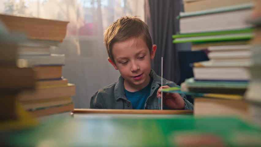 Child Reading and Studying at His Desk at Home Schoolboy Holding a Book Education and Homework Preparation for Learning and School. High quality 4k footage