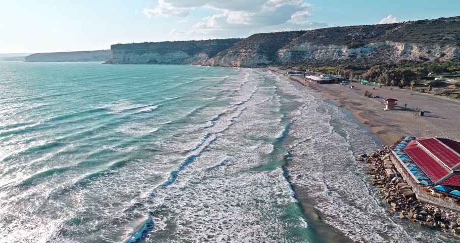 Aerial view of Kourion beach with rocks on the coast of the island of Cyprus. A beautiful landscape of nature at sunset, a vacation town near the sea. High quality 4k footage