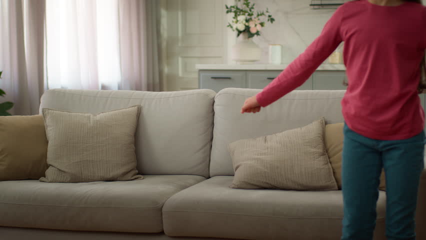 Happy laughing Caucasian family jumping on sofa mother woman female relaxing cuddle with joyful playful little girl child kid daughter playing watching TV resting bonding together inside new apartment