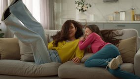 Happy laughing Caucasian family jumping on sofa mother woman female relaxing cuddle with joyful playful little girl child kid daughter playing watching TV resting bonding together inside new apartment - Powered by Shutterstock - Get 15% off with code: PIKWIZARD15