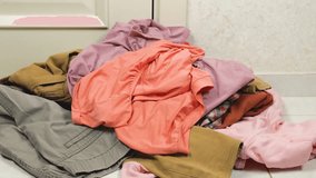 Colored shirts and t-shirts are thrown on a pile of laundry on the floor. The theme of washing, sorting clothes and cleaning the house. - Powered by Shutterstock - Get 15% off with code: PIKWIZARD15