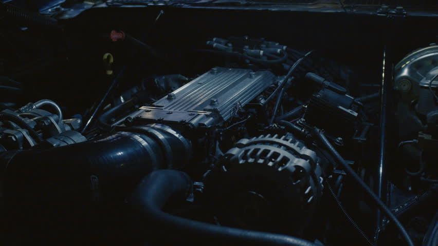 Close up shot of a sports car engine and system under the hood. Motor of a racing car up close. A close-up view of a car motor in low light, showcasing various components.