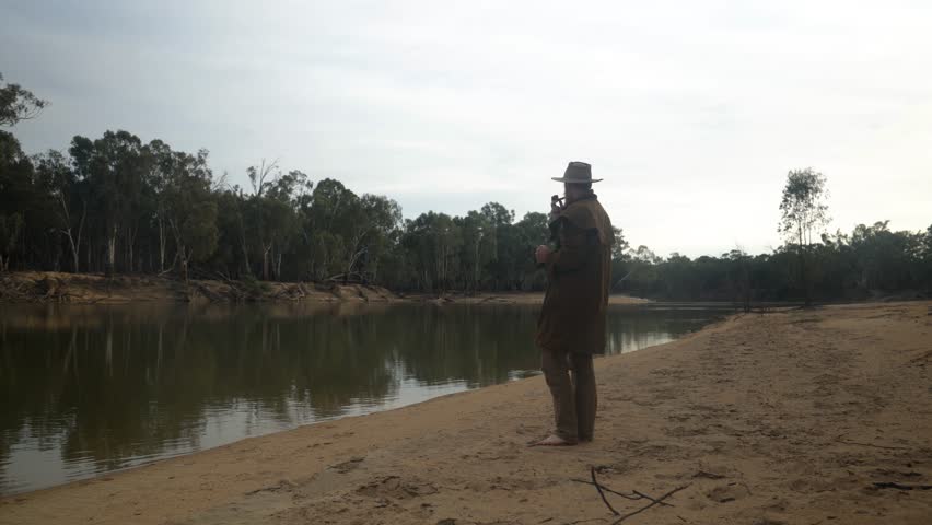 A bushman drinks a coffee while looking at the Murray river in the Australian outback.