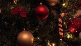 A close-up of a beautifully decorated Christmas tree featuring red and gold baubles, a candy cane, and a red ribbon, all illuminated by warm glowing lights. Perfect for capturing the festive spirit - Powered by Shutterstock - Get 15% off with code: PIKWIZARD15