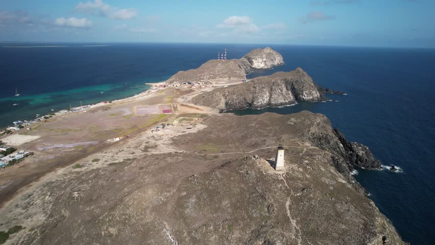 Gran roque island with its lighthouse and village, surrounded by the blue sea, aerial view