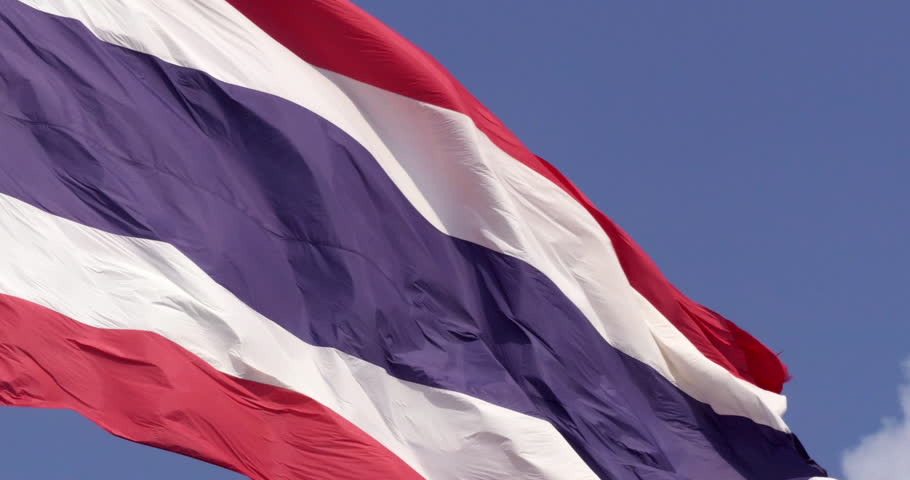 A majestic Thai flag fluttering in slow motion, set against a peaceful sky background. Experience the gentle motion of the Thai national flag, representing the country's enduring spirit and unity.