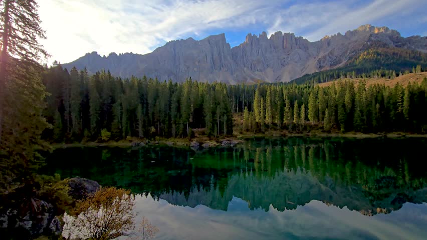 Experience the tranquil allure of a pristine Alpine lake illuminated by the soft light of dawn, framed by stunning mountain peaks and lush forests, Karersee lake Dolomites, Italy, lake Carezza