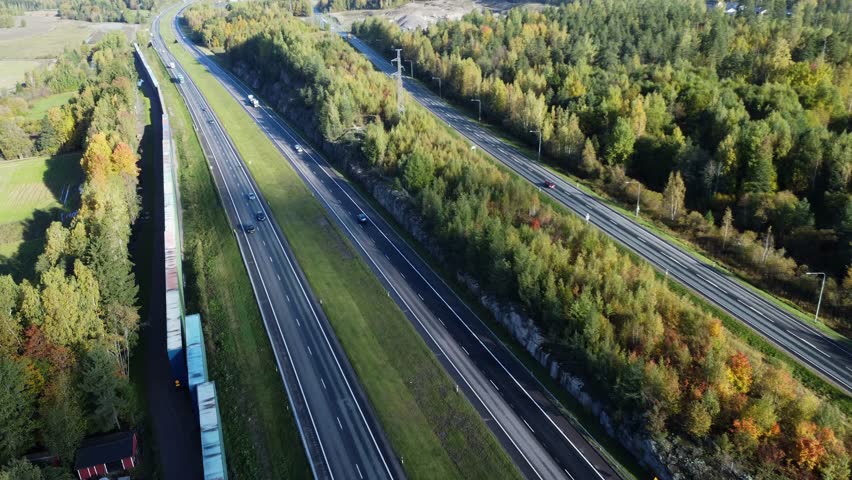Aerial view of highway vehicle traffic through northern autumn forest