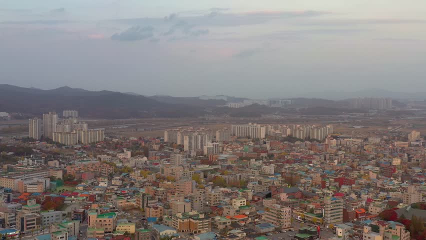 ASAN, SOUTH KOREA - OCTOBER 16, 2024: Aerial view of Asan city showcasing urban landscape and surrounding mountains during twilight