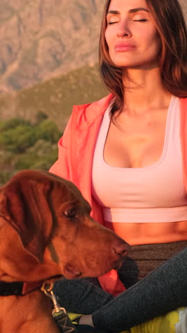 Silhouette of a slim woman on the beach at a beautiful sunset, Practice of yoga breathing techniques. a girl in sportswear sits on the sand and meditates, next to a dog on the beach