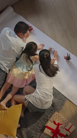 Top view of Happy young parents family drawing coloring picture with pencils enjoy creative art activity together. Asian mom dad and kid girl having fun in living room on leisure