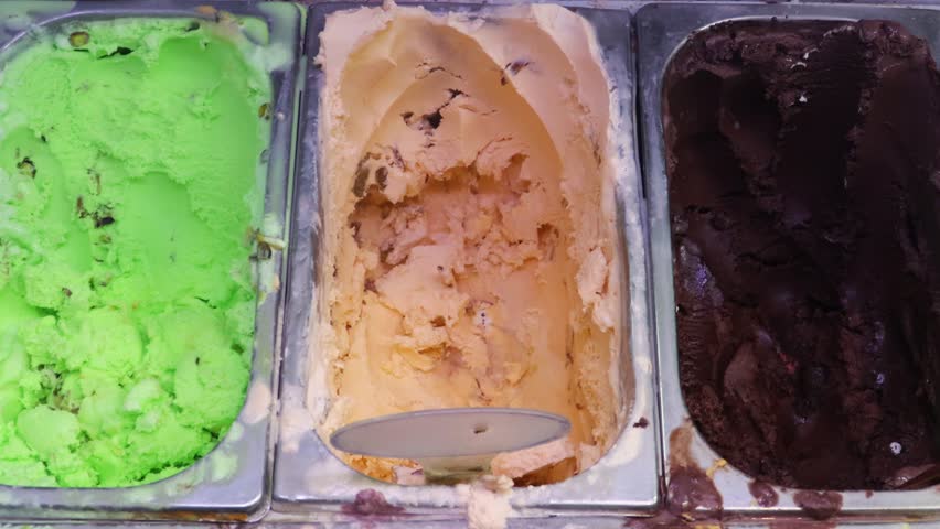 Ice cream parlour with different flavors in the refrigerator showcase. Tubs of ice cream.