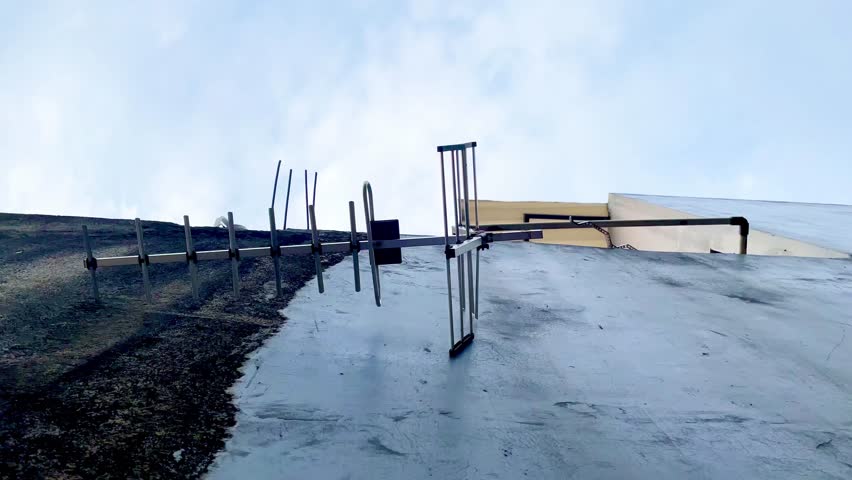 A large antenna is mounted on a building. The antenna is attached to a metal pole