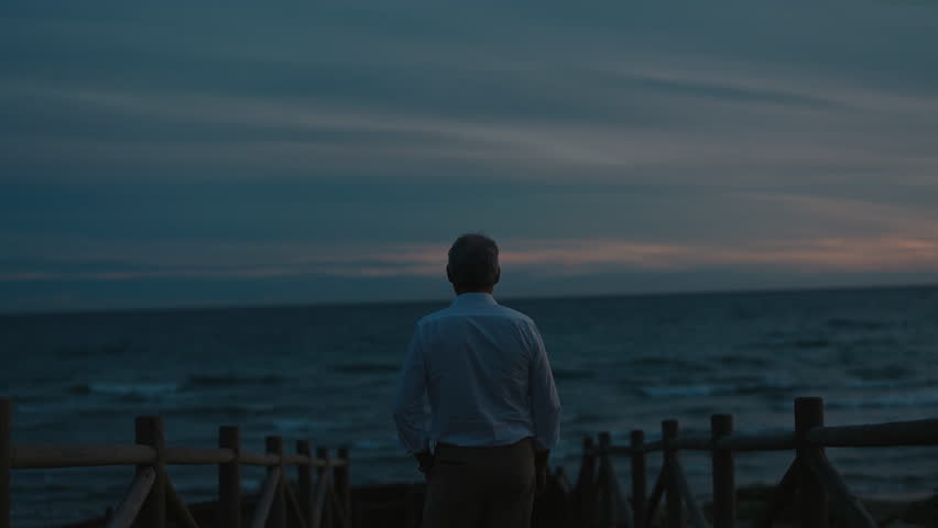 Lonely Aged Man Standing On Seashore. Back View.