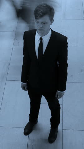 A Mysterious Individual Dressed in Formal Attire Standing Against an Urban Background