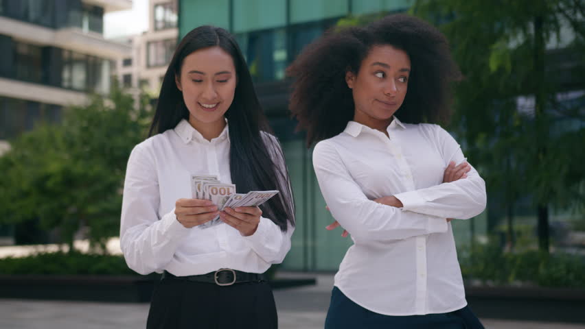 Asian Korean African American women count money salary bonus income envy arms crossed females inequality business financial colleague rivalry jealousy cash pay bills discrimination girls rich outdoors